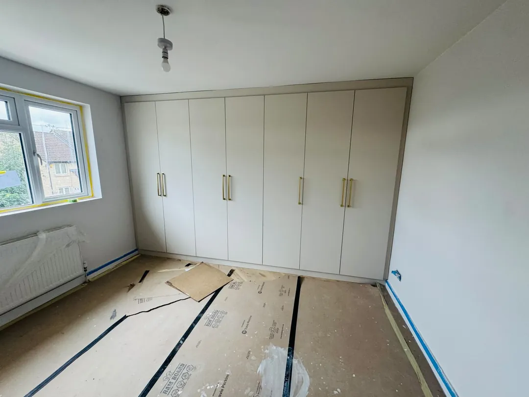 Before: Empty bedroom fitted out with full-height wardrobes
